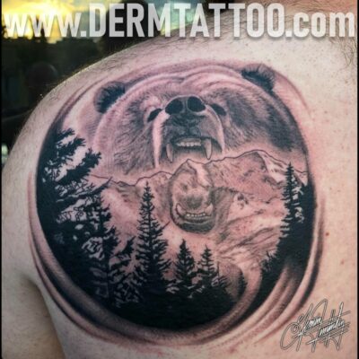A black and grey tattoo of a roaring bear with pine trees.