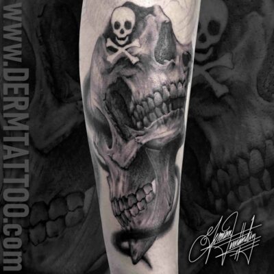 Black and gray skull tattoo on forearm with ghostly hooded figure.